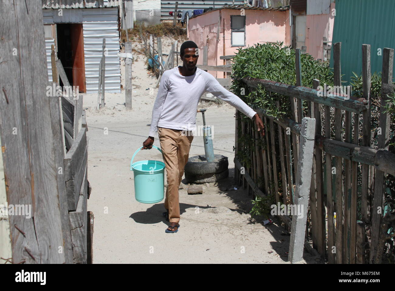 09 febbraio 2018, Sud Africa, Cape Town, Khayelitsha: Anele Goba, 34, che vive nella baraccopoli di Khayelitsha zona fuori Città del Capo, dispone di trasportare acqua da un rubinetto comunale alla sua capanna ogni giorno. Ha poca simpatia per la classe media, che teme "zero hour', quando Cape Town ha per spegnere l'acqua a causa della siccità. Foto: Kristin Palitza/dpa Foto Stock