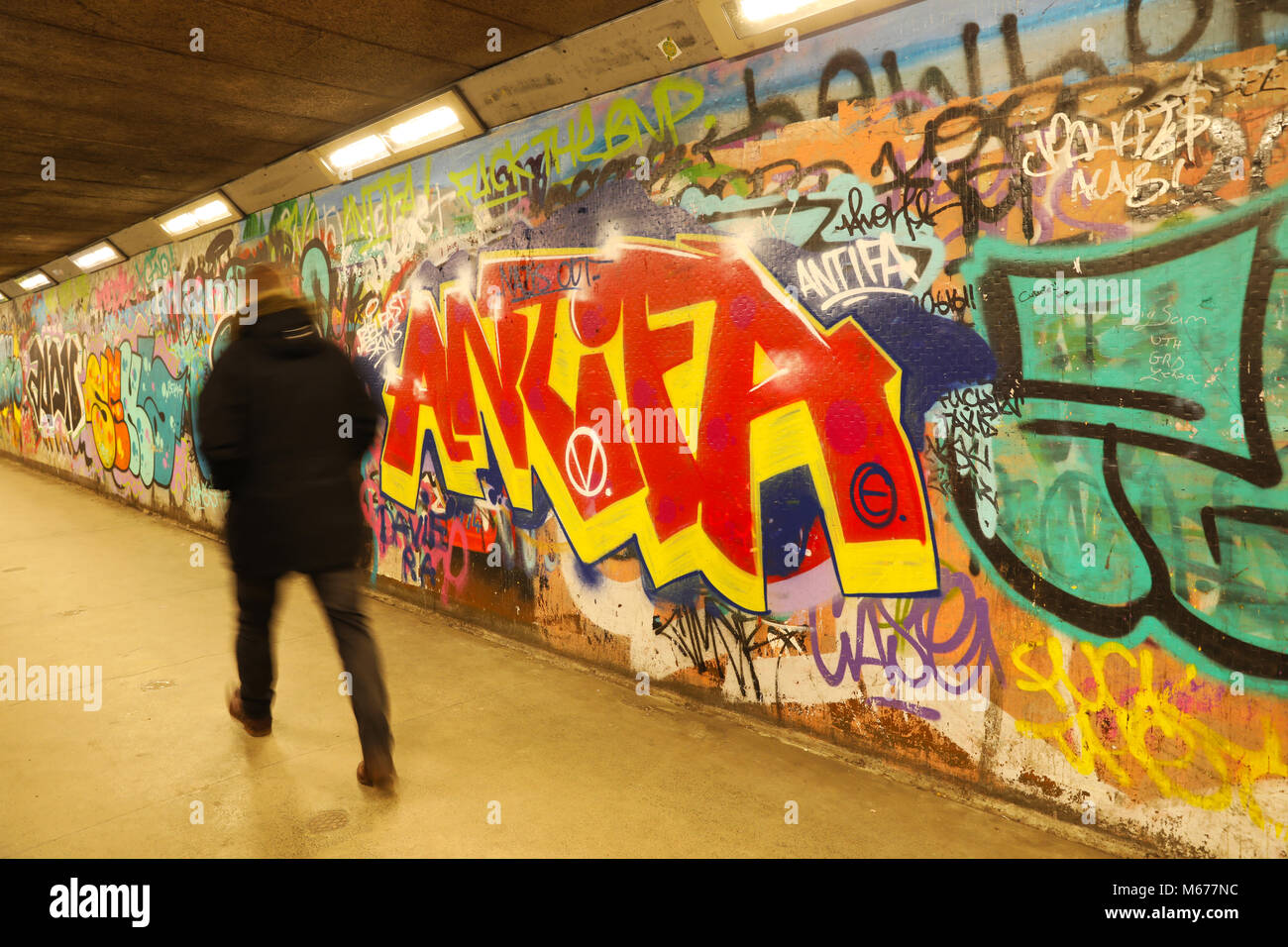 L'uomo cammina passato un ANTIFA grafitti pezzo giù una metropolitana Foto Stock