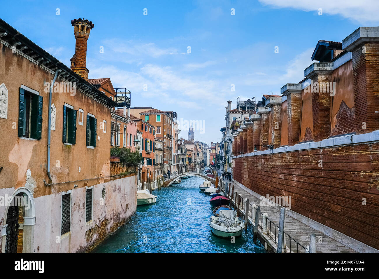 Canali d'acqua a Venezia con barca in movimento, nessuna folla e nessuna persona identificabile durante l'inverno e cieli bianchi limpidi. Foto Stock