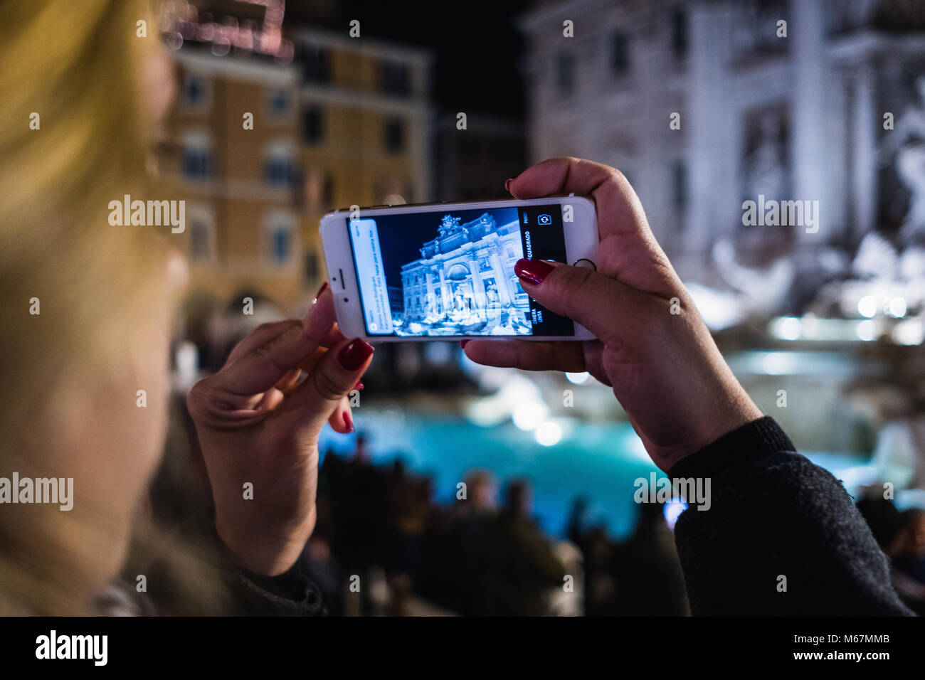 Donna con telecamera mobile per fotografare la Fontana di Trevi a Roma di notte Foto Stock