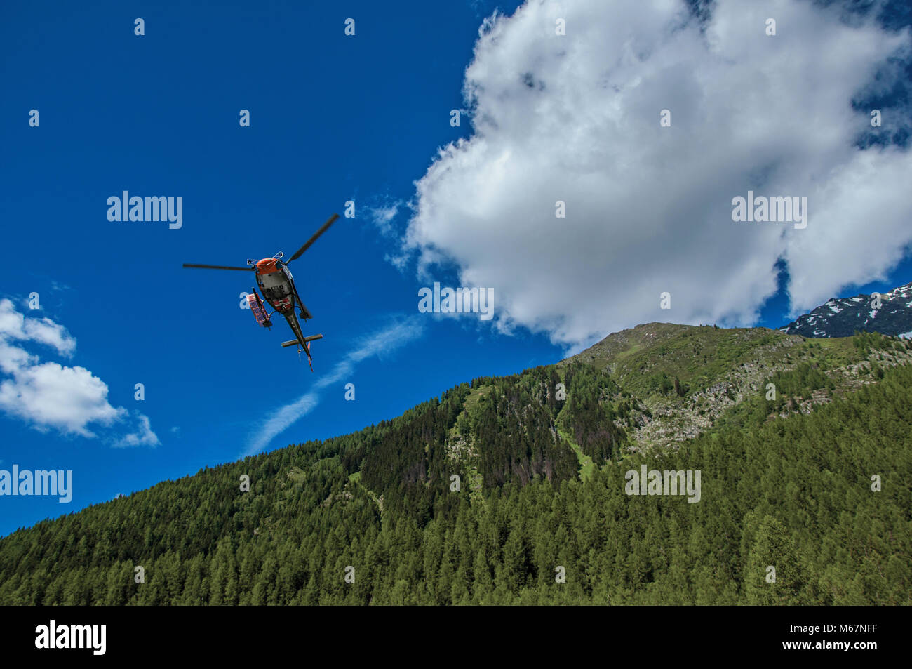 Elicottero di decollare in una foresta a Argentiere, un piccolo villaggio alpino con diversi percorsi di trekking in estate. Vicino a Chamonix nelle Alpi francesi Foto Stock