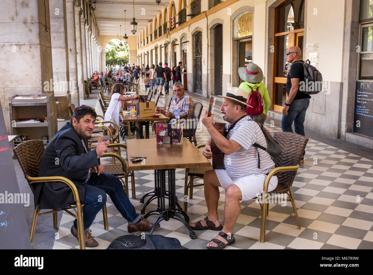 La mezza età uomo a suonare la chitarra e cantare in Pavement Cafe, Plaça de la Independencia, Girona, Catalogna, Spagna Foto Stock