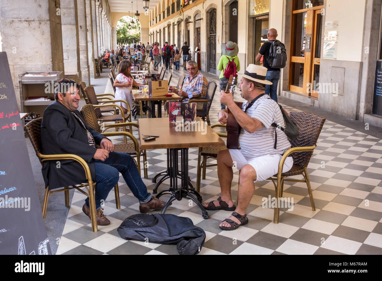 La mezza età uomo a suonare la chitarra e cantare in Pavement Cafe, Plaça de la Independencia, Girona, Catalogna, Spagna Foto Stock