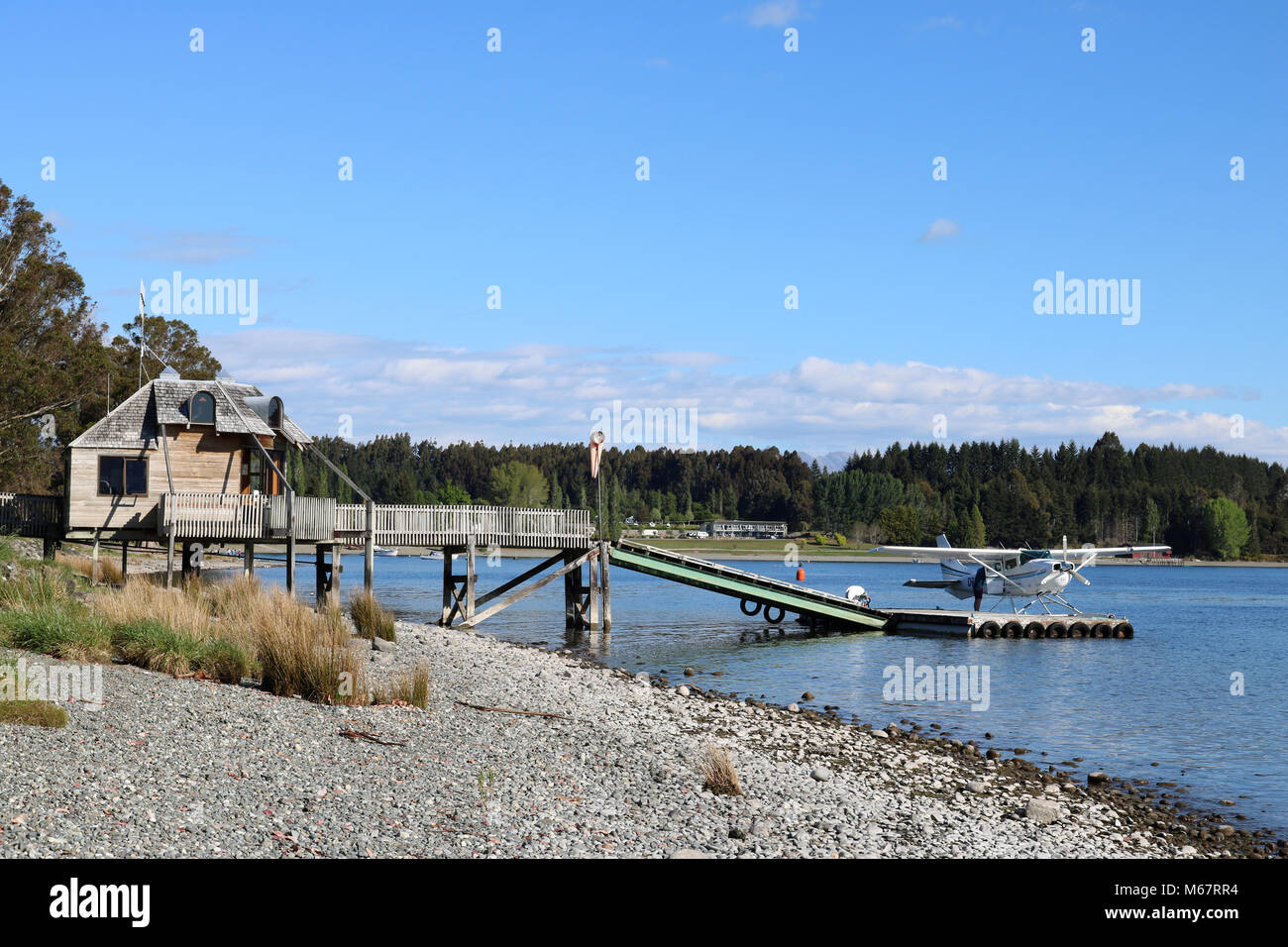 Vista lungo la riva del Lago Te Anau a Te Anau a Southland, Isola del Sud della Nuova Zelanda guardando verso la banchina e pontile con idrovolante sul lago. Foto Stock