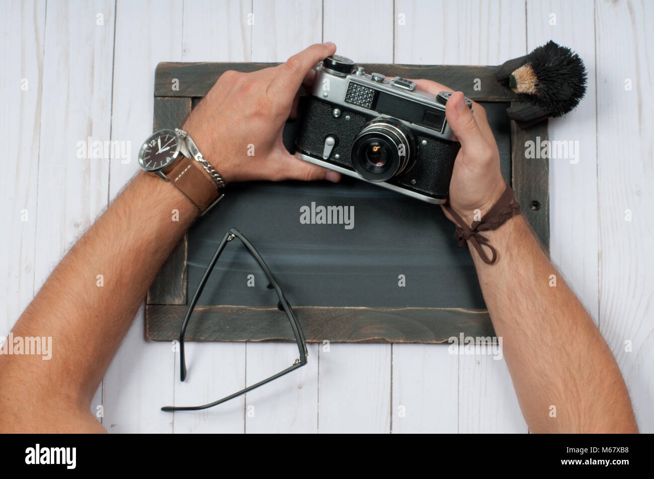 Gli uomini di accessori. Gli uomini con le mani in mano tenere la fotocamera su sfondo di legno Foto Stock