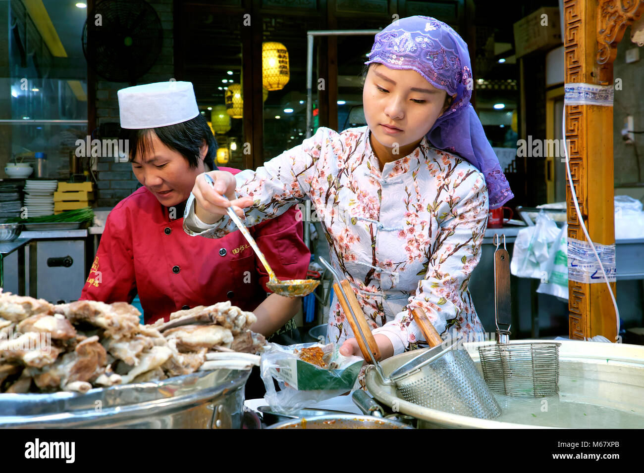 Giovani Musulmani Hui donna che lavorano presso il mercato alimentare, il Quartiere Musulmano Bazaar, Beiyuanmen Street, Xi'an, Shaanxi Province, Cina Foto Stock