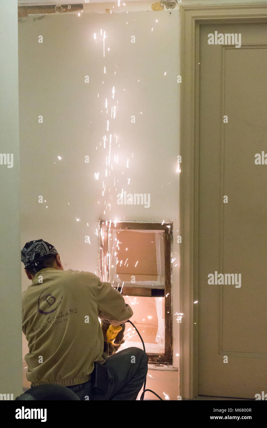 Lavoratore utilizzando acciaio utensile smerigliatrice in appartamento edificio corridoio rinnovo, New York City, Stati Uniti d'America Foto Stock