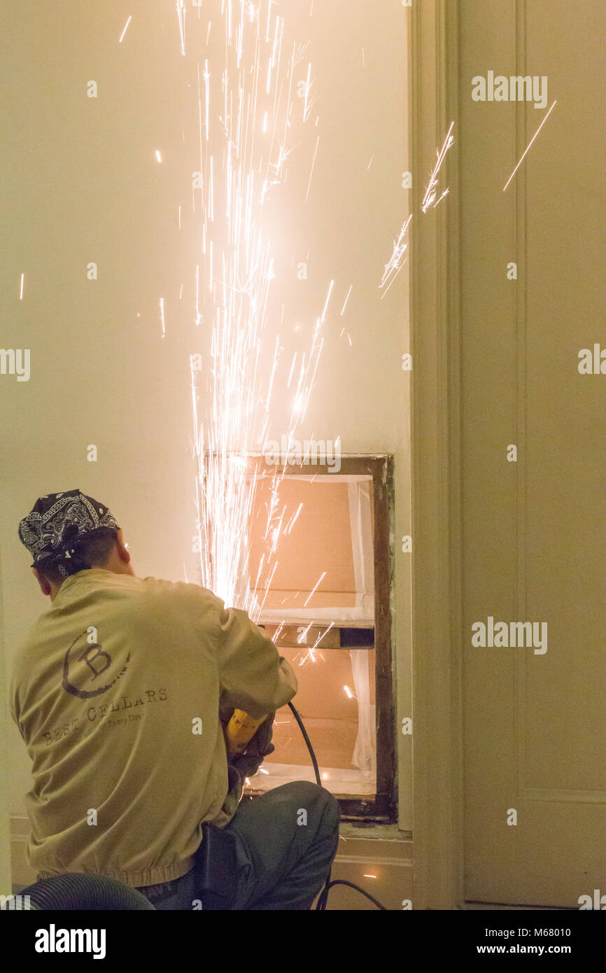 Lavoratore utilizzando acciaio utensile smerigliatrice in appartamento edificio corridoio rinnovo, New York City, Stati Uniti d'America Foto Stock