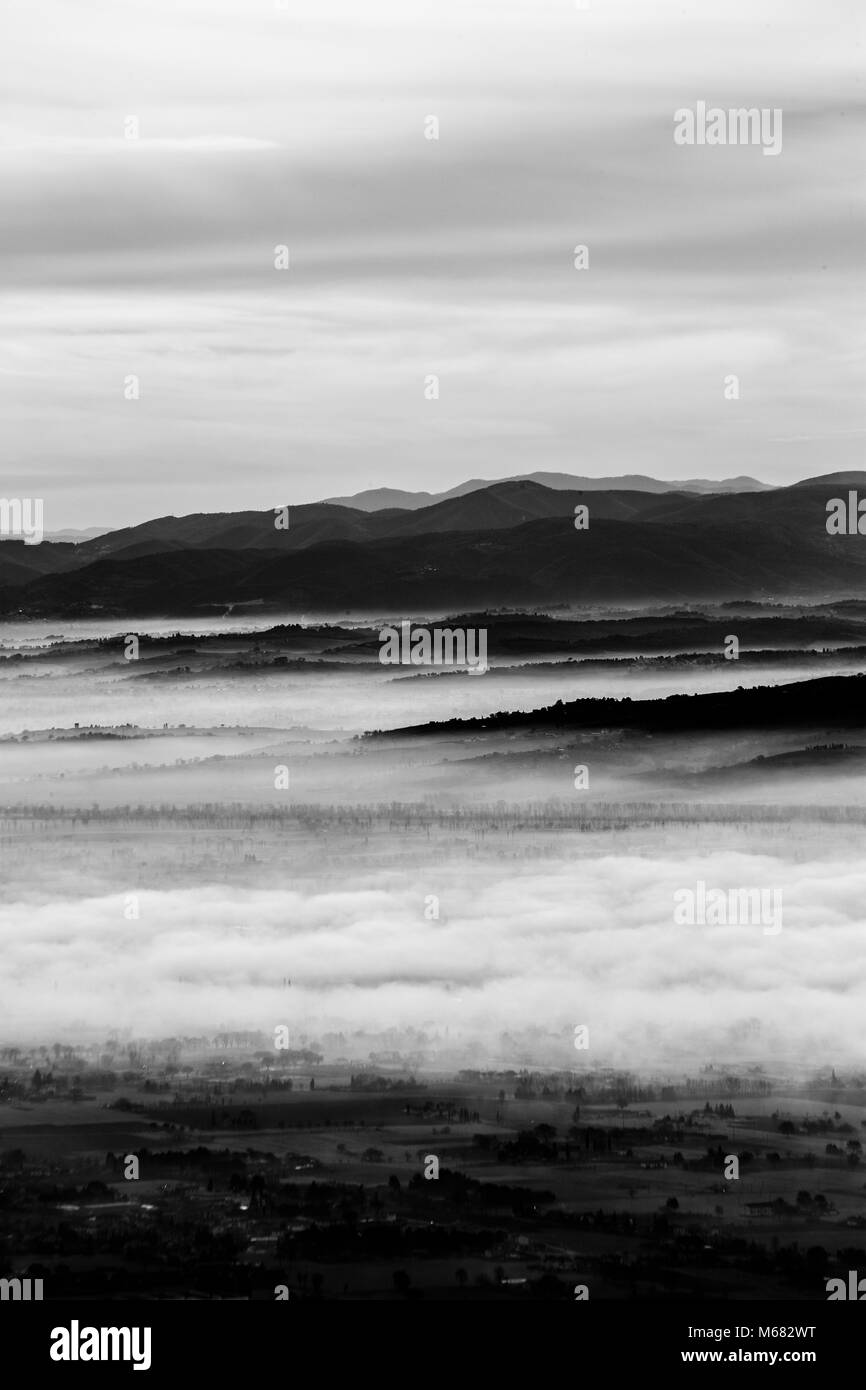 Splendida vista della valle umbra in un inverno mattina, con la nebbia che copre gli alberi e le case Foto Stock