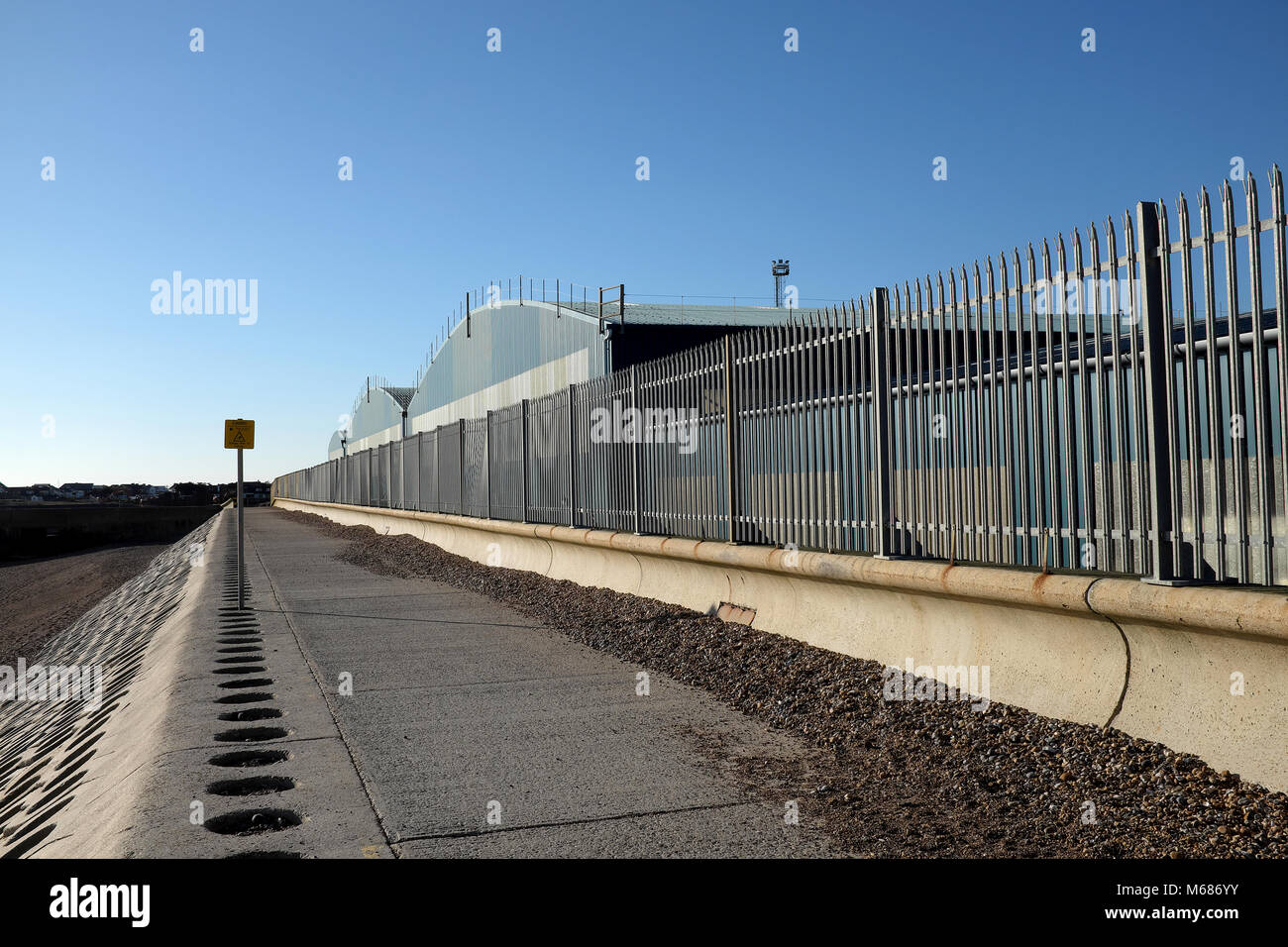 Shoreham porta, West Sussex, in Inghilterra. Le difese del mare e lo stoccaggio in Bulk capannoni accanto al monarca del cammino di lunga distanza sentiero, Southwick Beach. Foto Stock