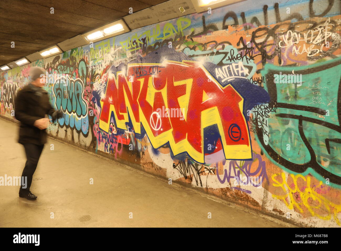 Uomo che cammina davanti a un ANTIFA graffiti pezzo in una metropolitana Foto Stock