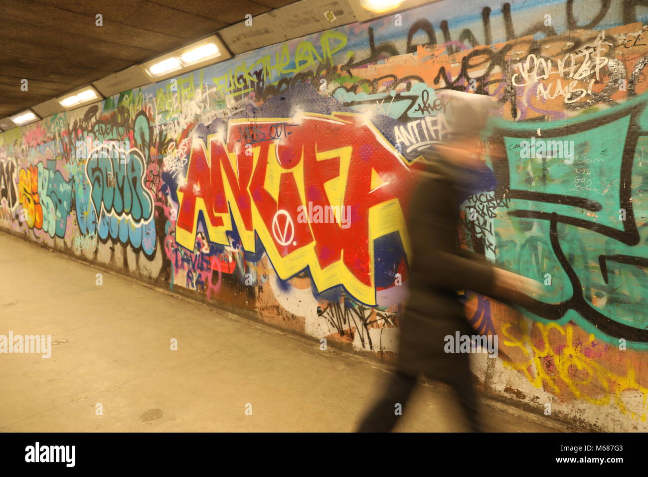 Uomo che cammina davanti a un ANTIFA graffiti pezzo in una metropolitana Foto Stock
