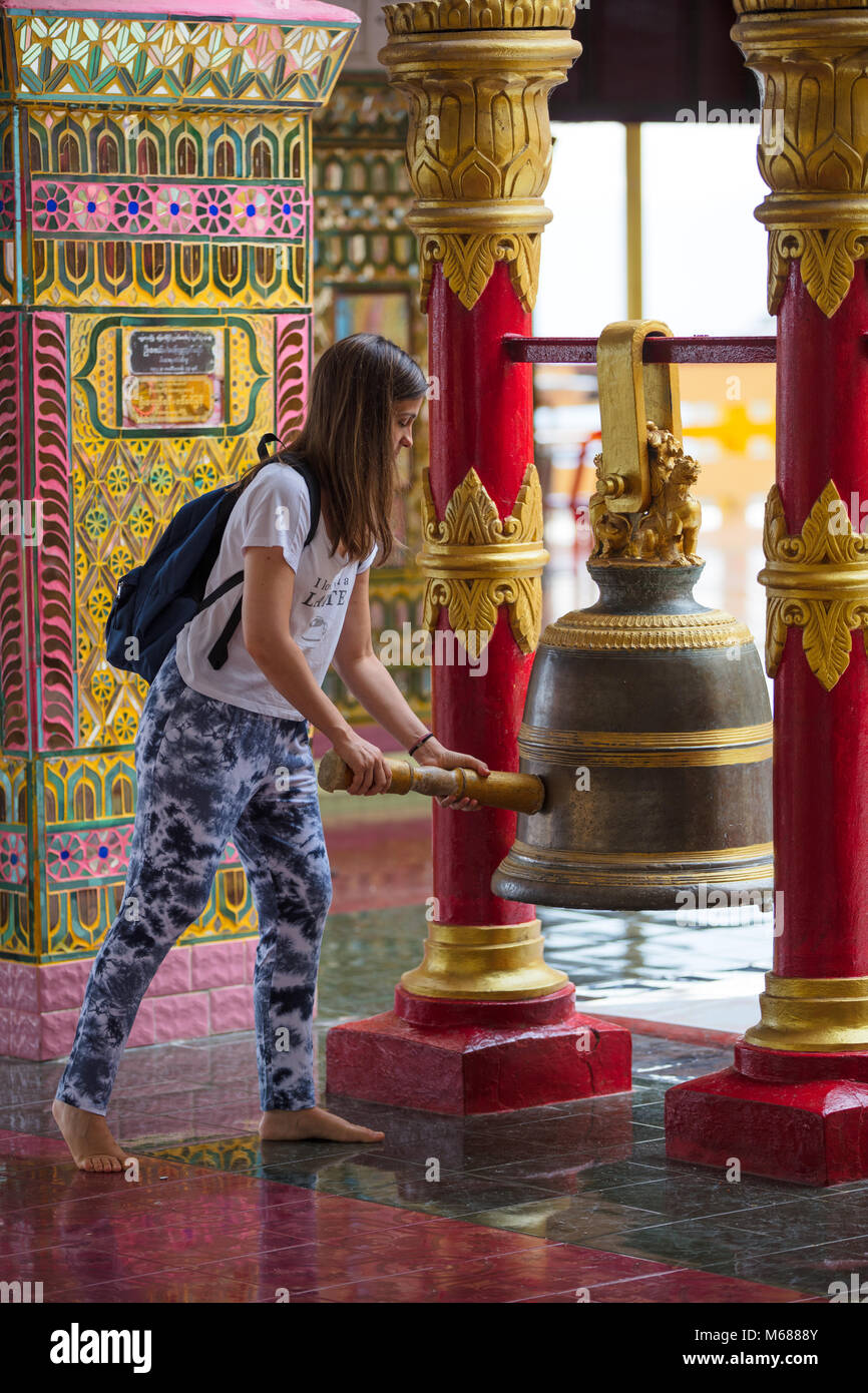 Un turista di interagire con una campana buddista all'interno della Pagoda Sutaungpyei. Mandalay Hill, Myanmar (Birmania). Foto Stock