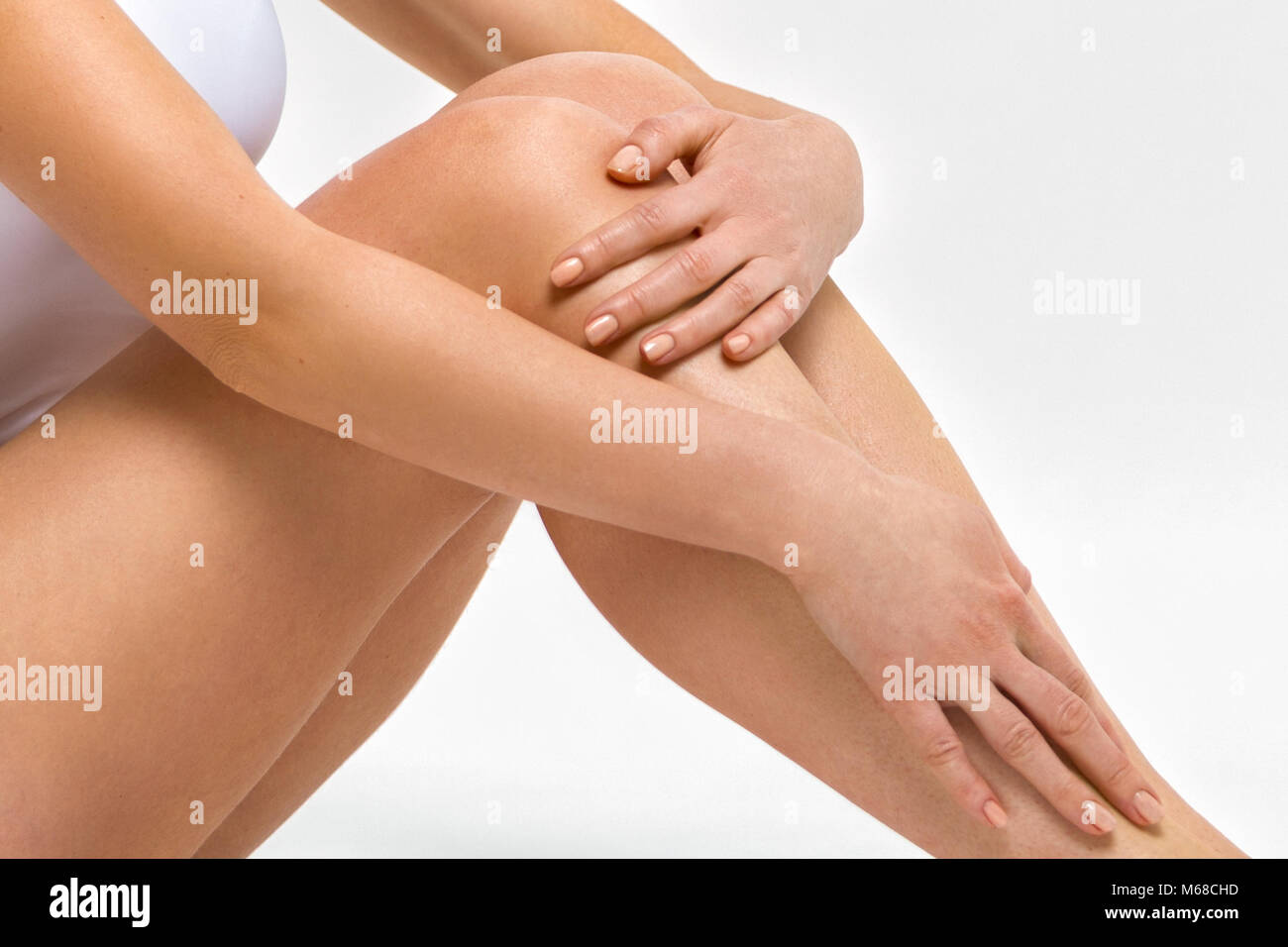 Belle gambe femmina. Una donna sta abbracciando le ginocchia. Foto in studio close up Foto Stock