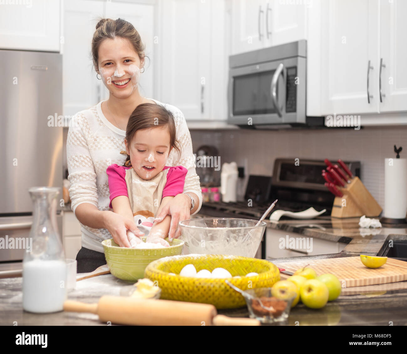 La famiglia felice in cucina, madre e figlia la cottura della torta di mele, mescolare l'impasto Foto Stock