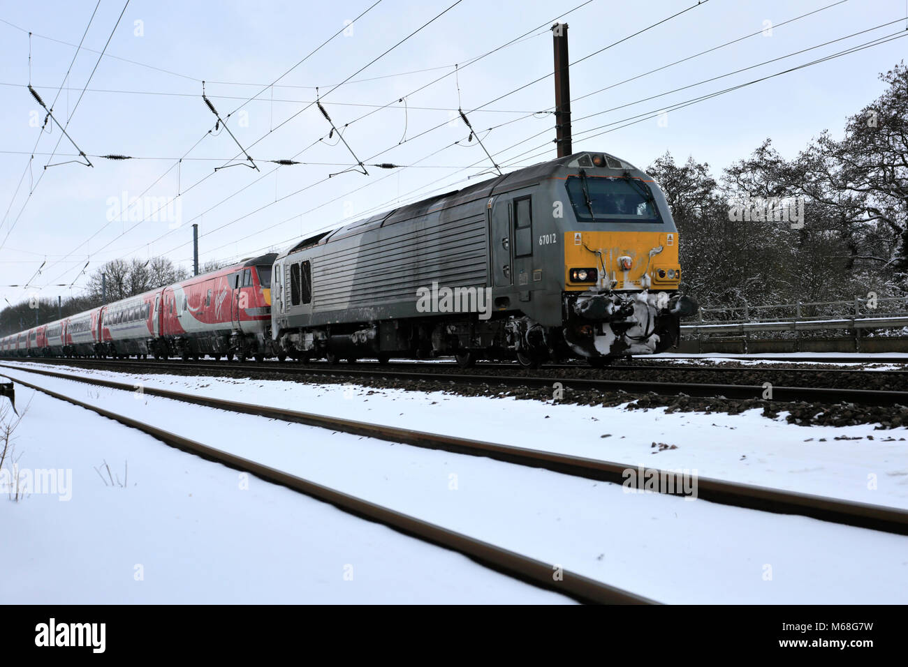 In inverno la neve, Chiltern Railways 67012 tirando ripartiti vergine treno, East Coast Main Line Railway, Peterborough, CAMBRIDGESHIRE, England, Regno Unito Foto Stock