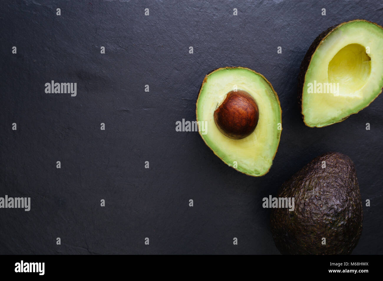 Metà di Avocado overhead su sfondo scuro Foto Stock