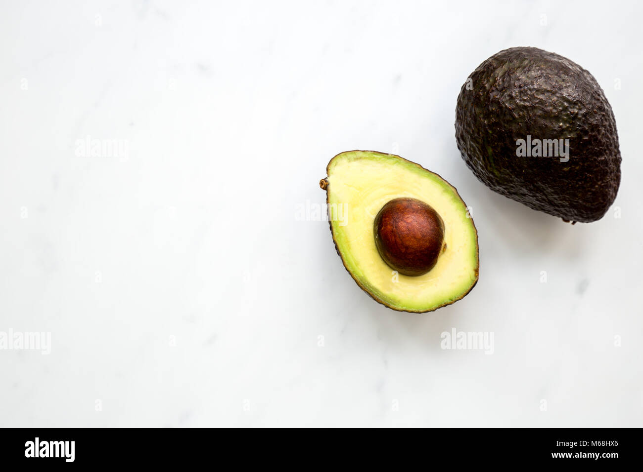 Metà di Avocado overhead su marmo bianco sullo sfondo Foto Stock