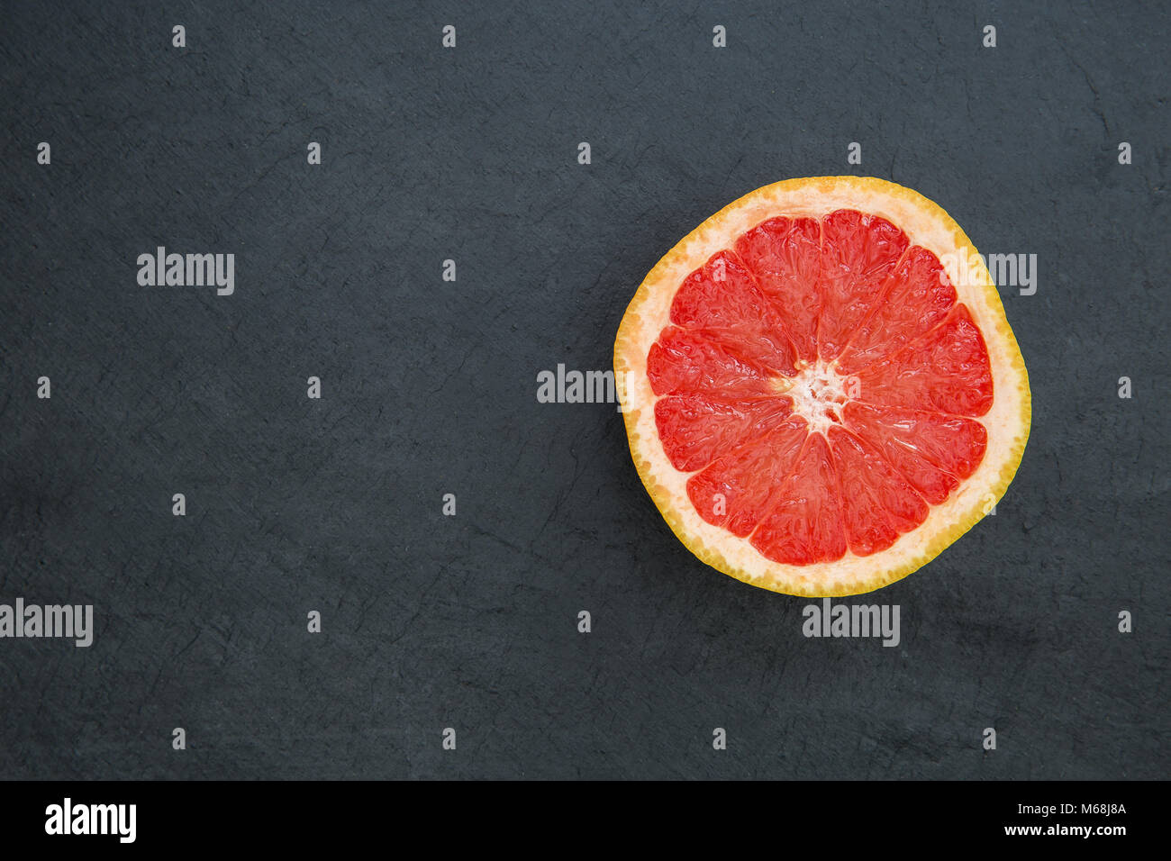 Pompelmo rosa per metà su sfondo scuro con spazio di copia Foto Stock