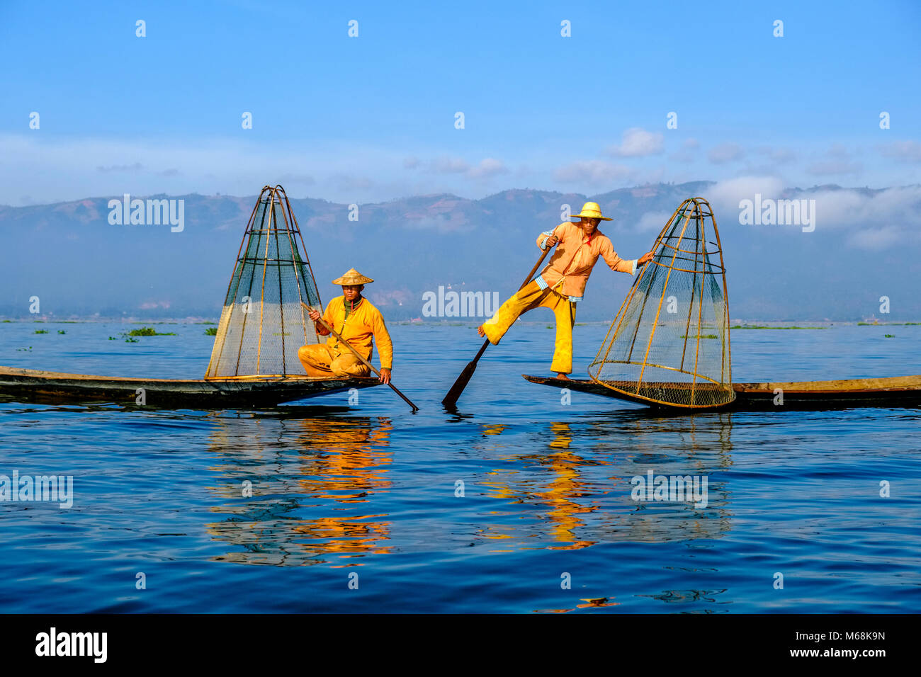I pescatori, in piedi sulle loro barche, posa, sono la pesca in modo tradizionale sul Lago Inle Foto Stock