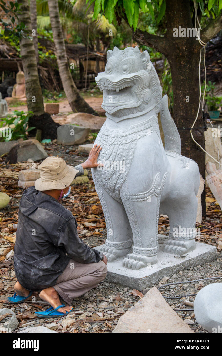Un intagliatore di pietra mette tocchi di finitura su una scultura in pietra in Cambogia. Foto Stock