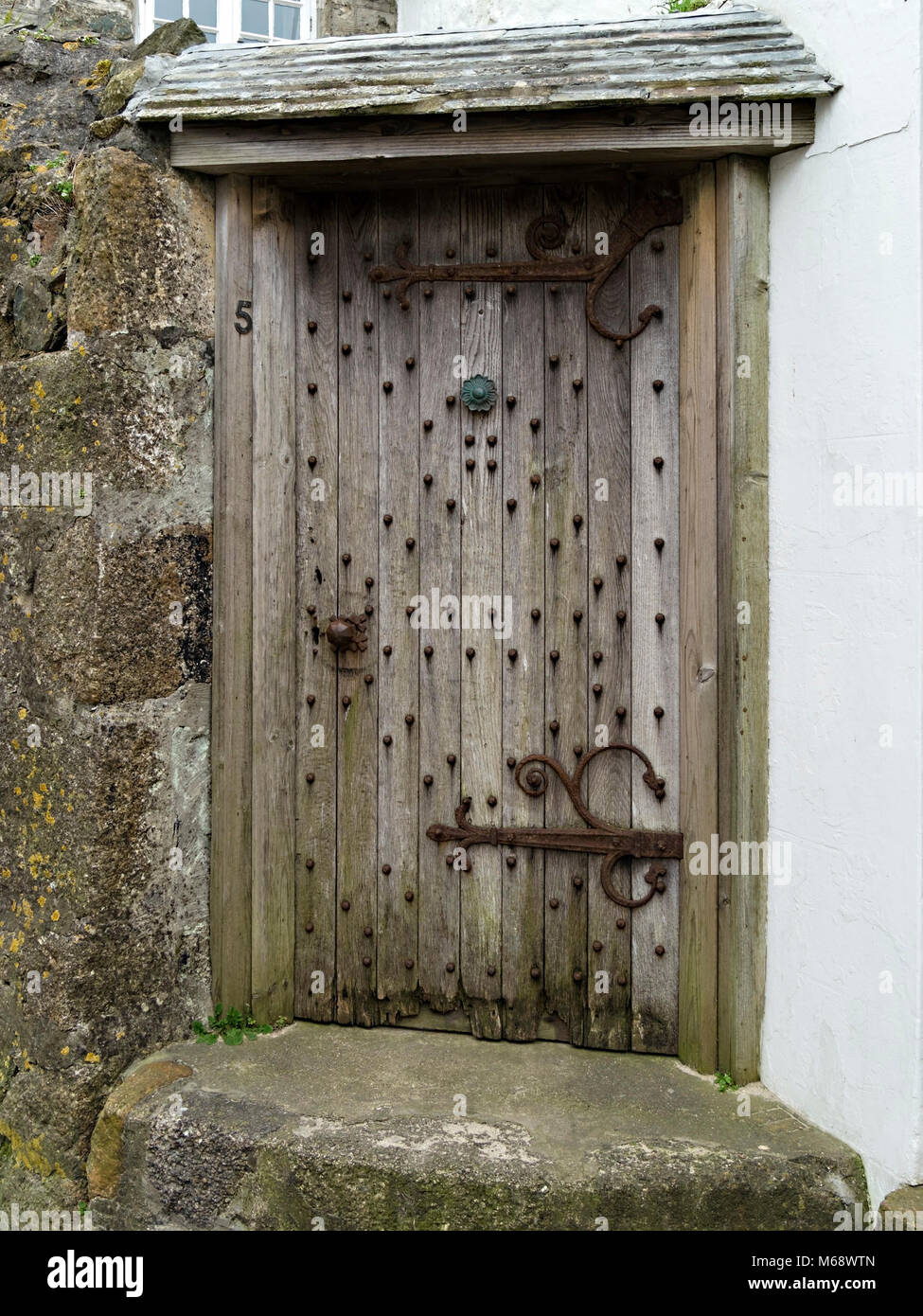 Quercia antica porta anteriore con raccordi di ferro in granito muro di pietra di ciò che viene ripetutamente la più antica casa di St. Ives, Cornwall, Regno Unito Foto Stock