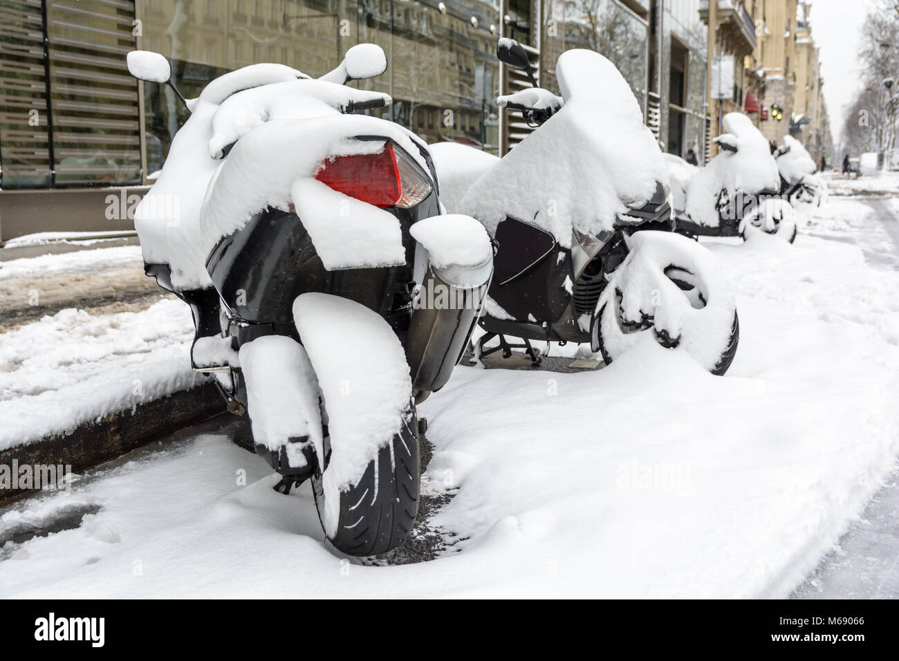 Coperte di neve scooter e moto parcheggiate all'aperto per le strade di Parigi. Foto Stock