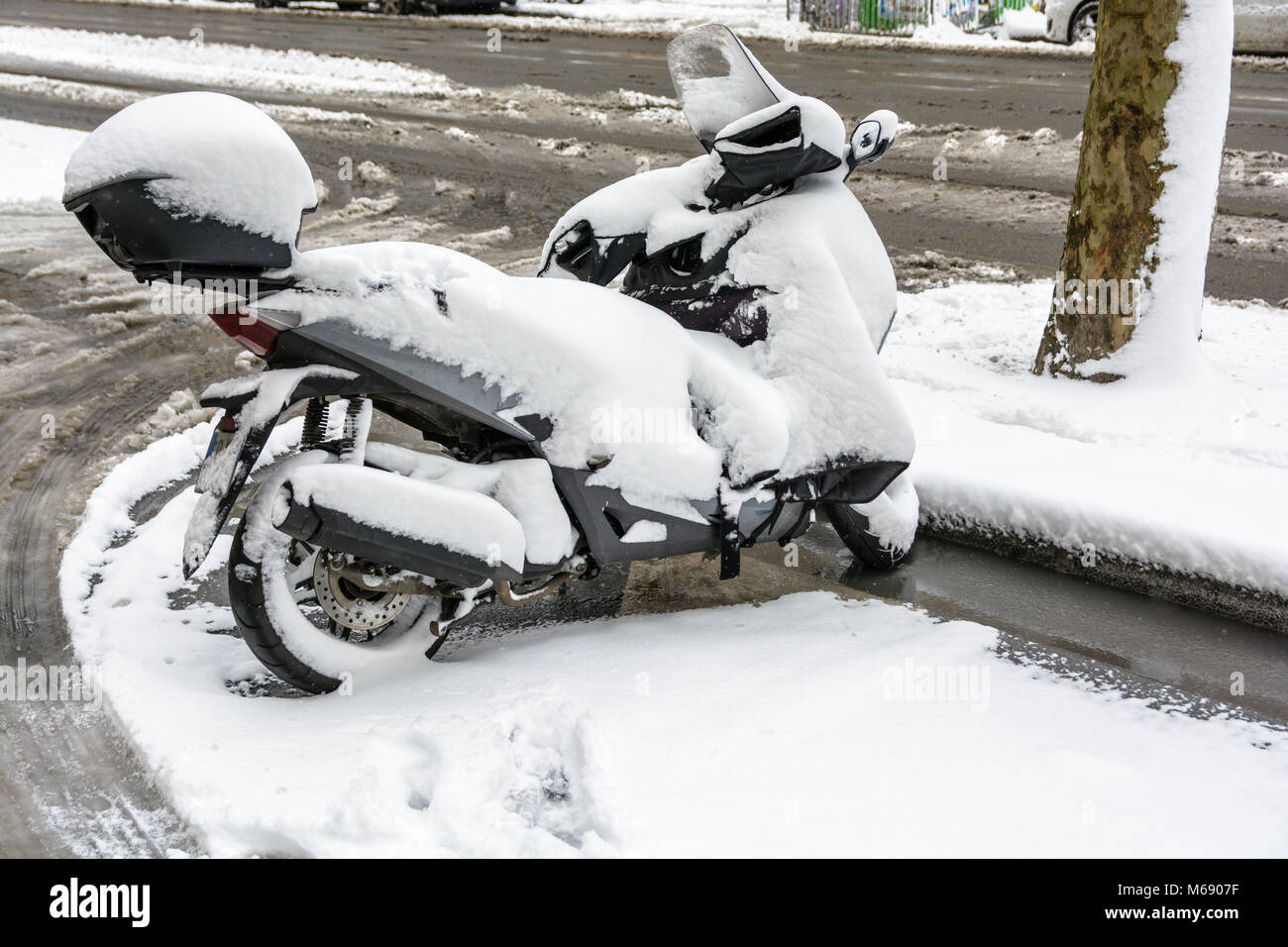 Una coperta di neve scooter parcheggiato all'aperto per le strade di Parigi in un giorno d'inverno. Foto Stock