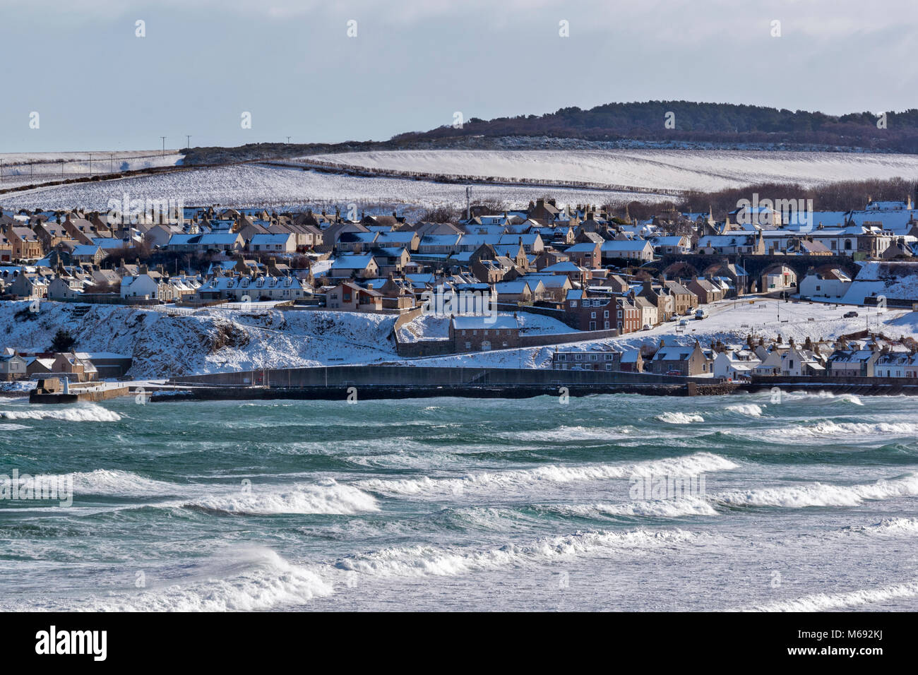 MORAY COAST SCOZIA Cullen Bay grandi onde sul mare e in inverno la neve sul porto e CASE IN CITTÀ Foto Stock
