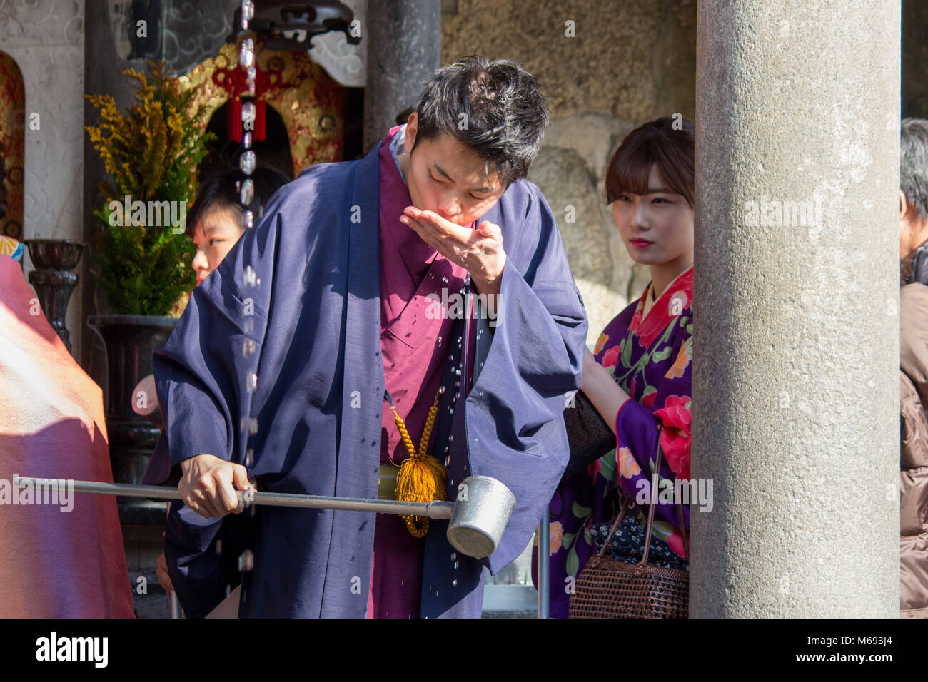 Un uomo dentro il Kiyomizu-dera tempio Buddista bevande acqua sacra dal santuario Jishu nell'area di Gion di Kyoto, Giappone. Foto Stock