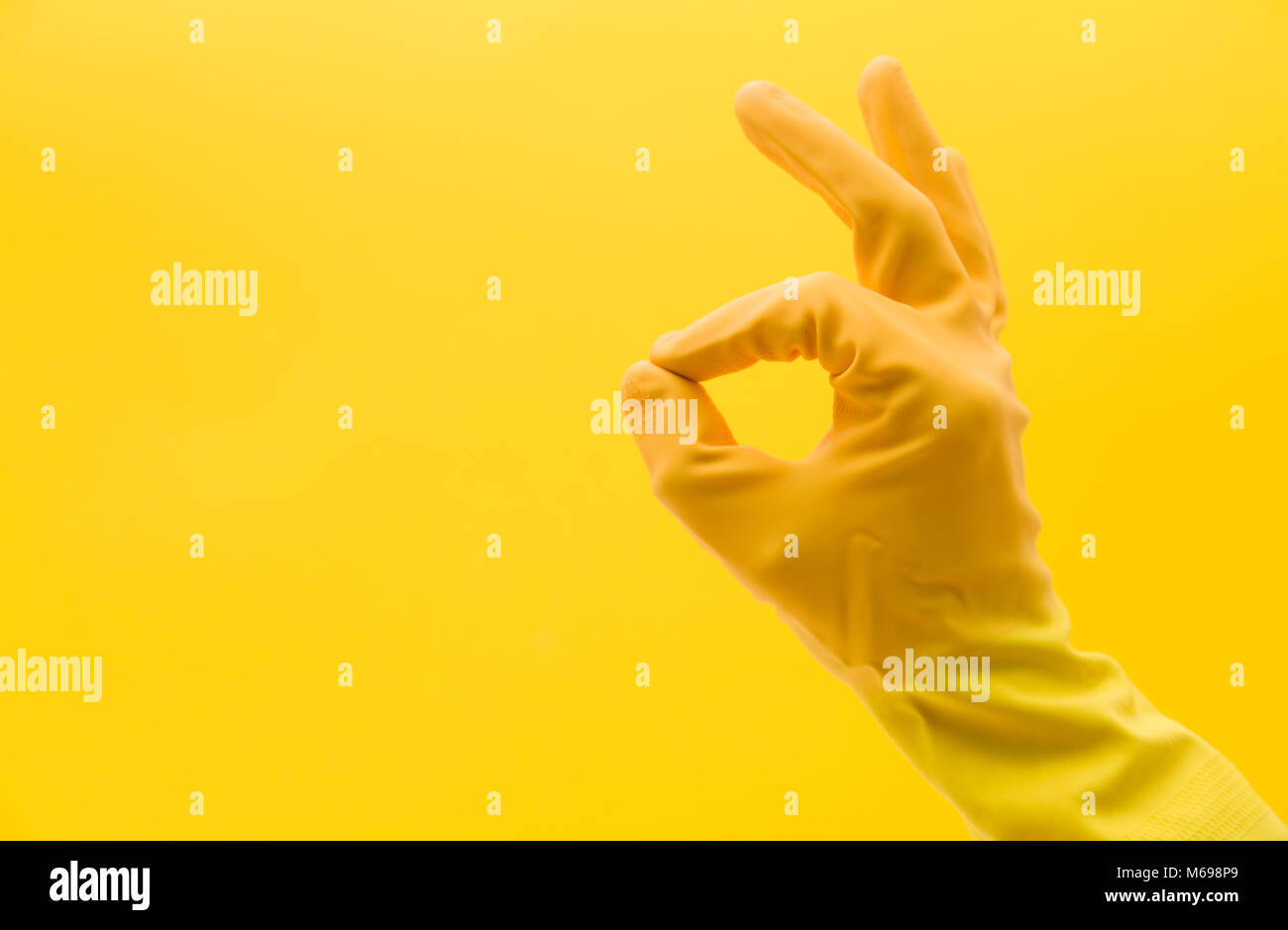 Okay mano gesto di una mano in una gomma gialla guanto di pulizia Foto Stock