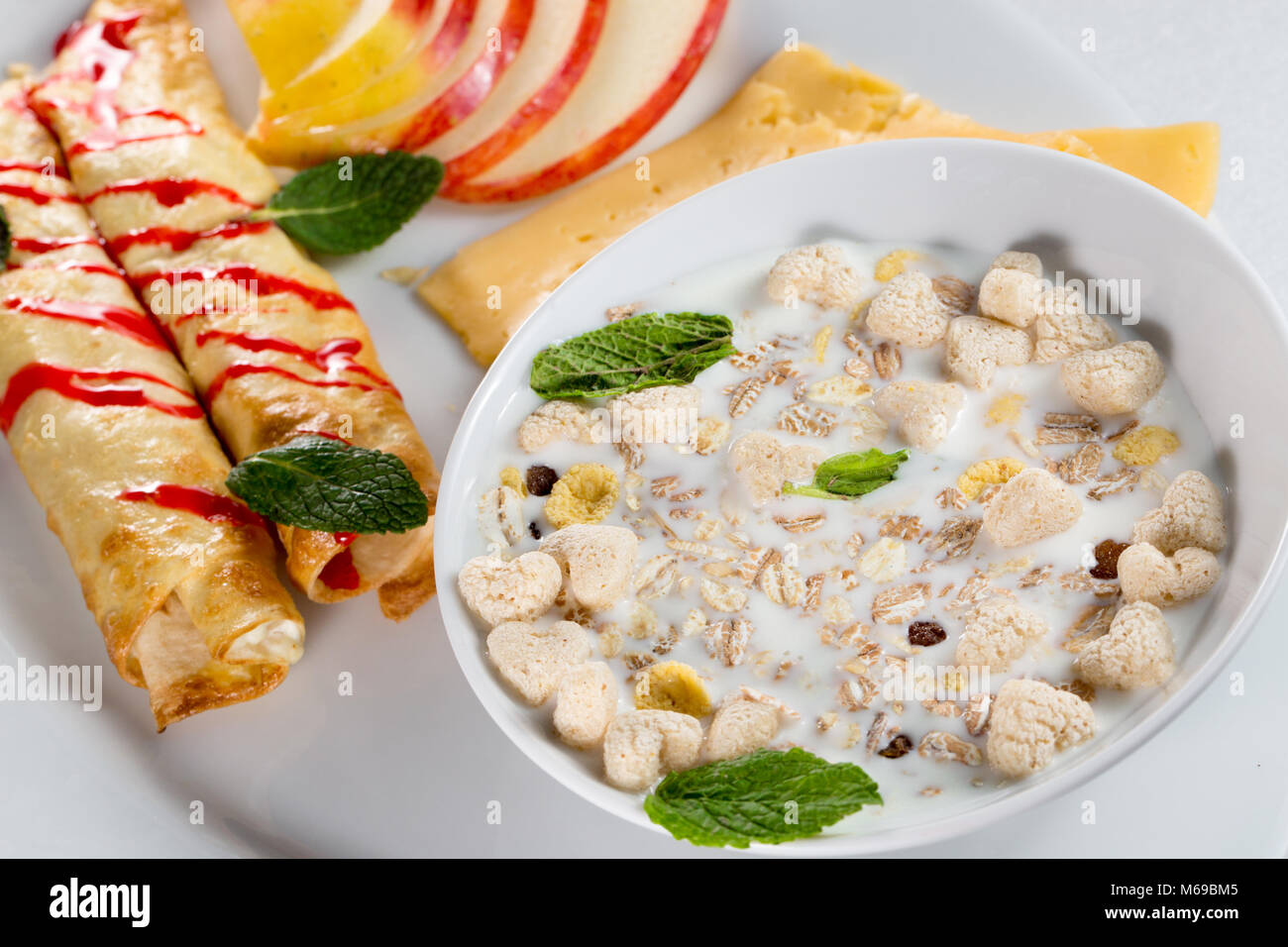 La prima colazione con frittelle di mele, formaggio e muesli con latte. Foto Stock