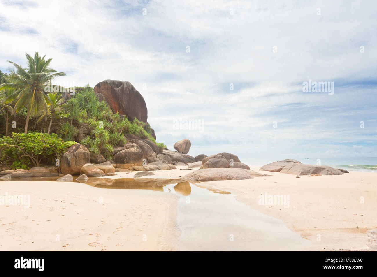 Bentota, Sri Lanka, Asia - un piccolo fiume di fronte a enormi rocce di granito e palme Foto Stock