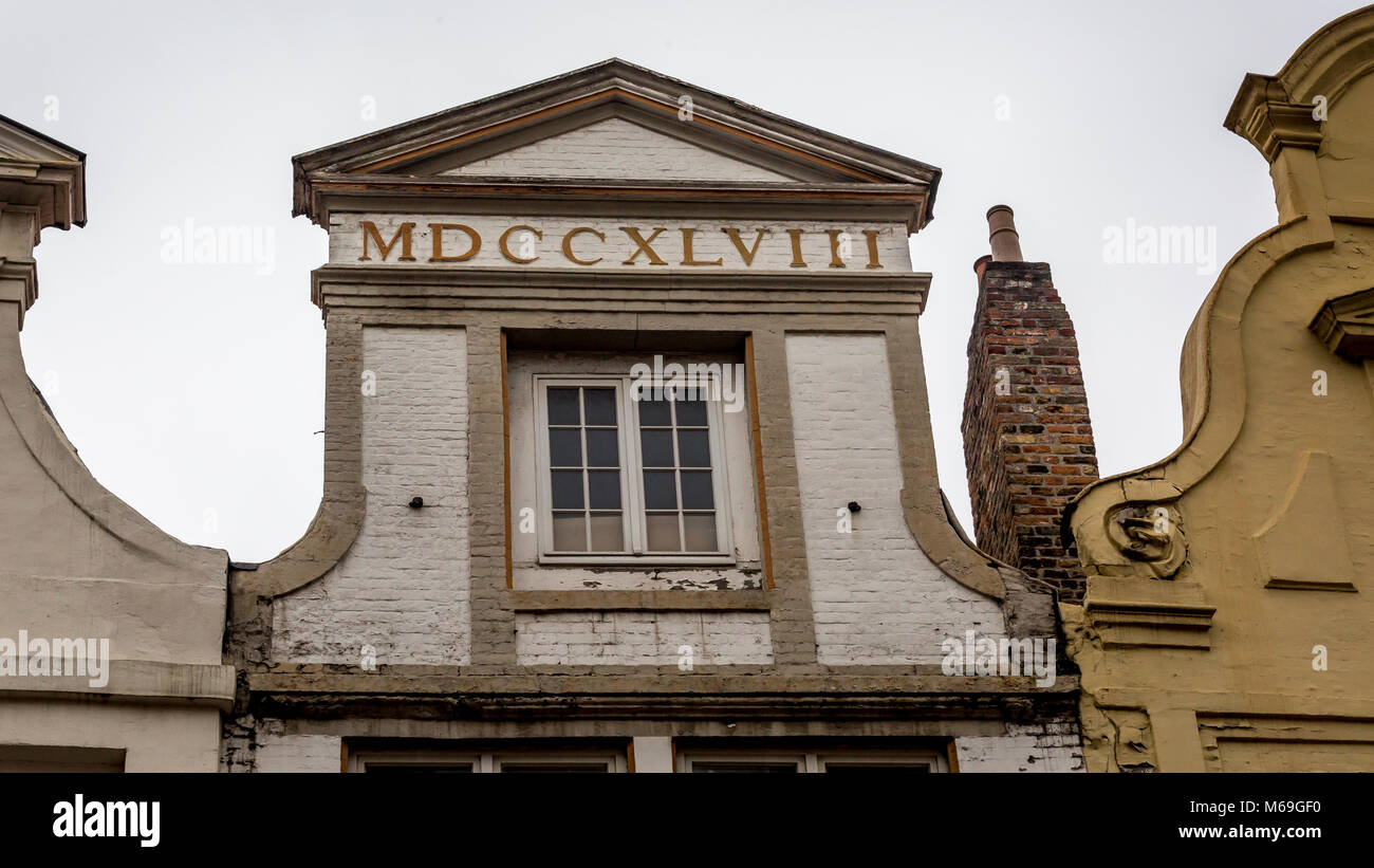 Palladiano tetto a forma di facciata con la data 1748 visualizzati in numeri romani su un quadrato sul telaio di una finestra nel campo architettonico laden città di Bruges Foto Stock