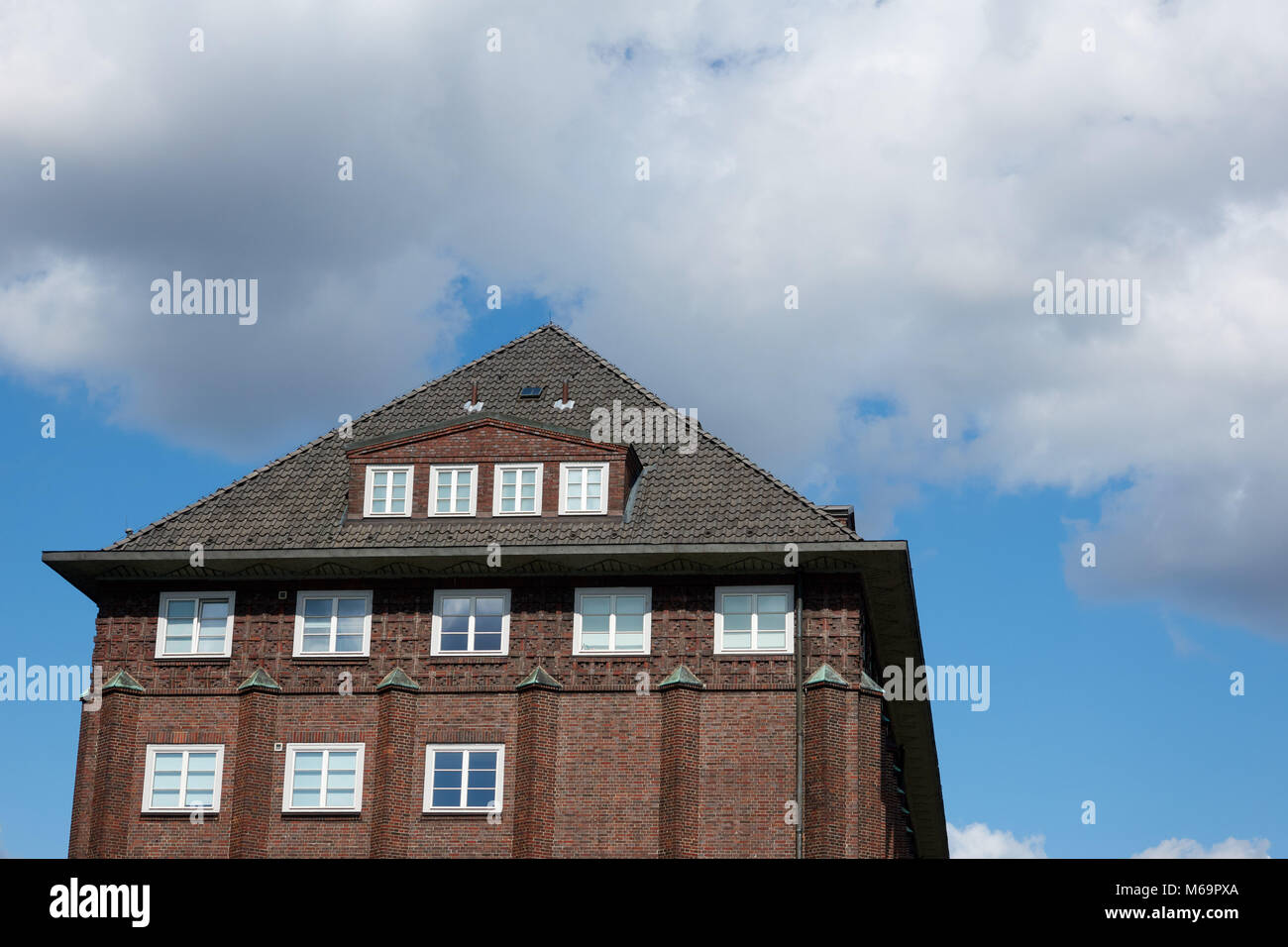 Il tetto di una vecchia casa in mattoni rossi contro un cielo blu e nuvole di Amburgo. Foto Stock