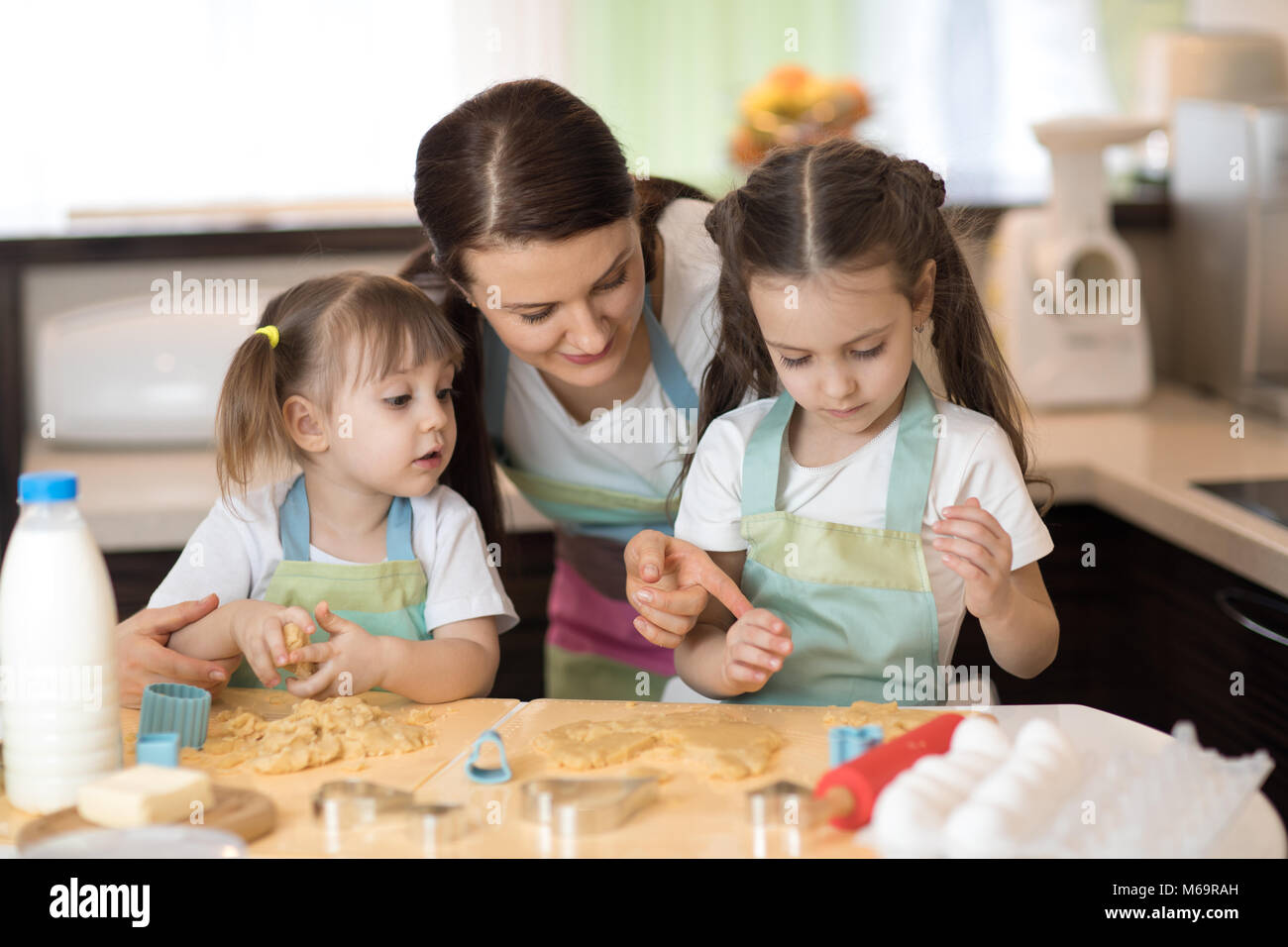 La mamma con il suo 2 e 5 anni sono figlie della cottura in cucina domestica per la festa della mamma Foto Stock
