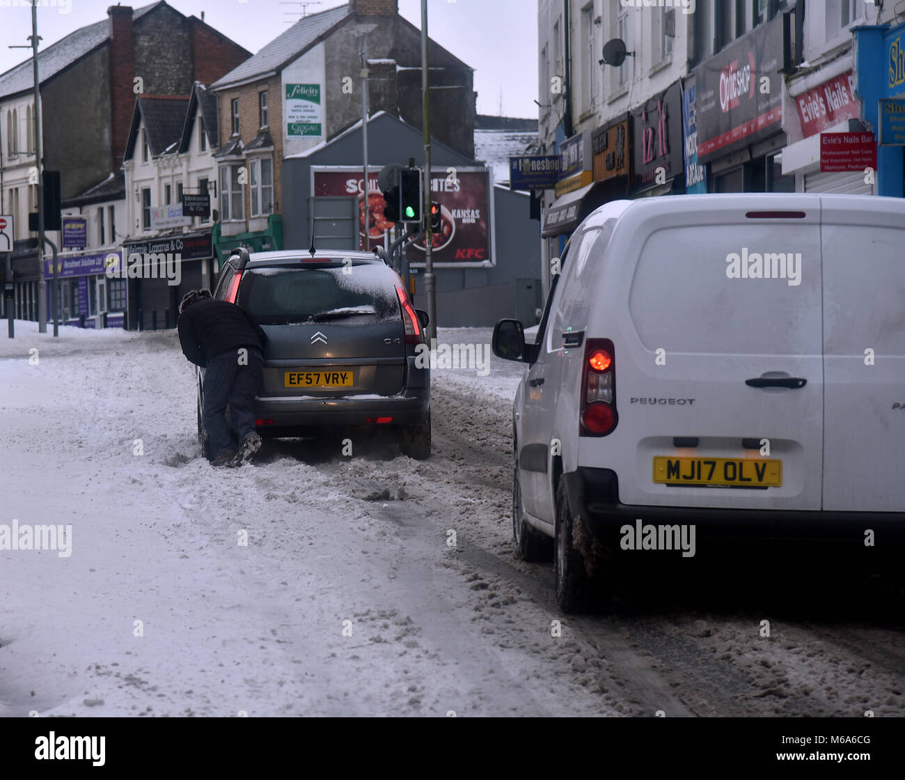 Le immagini mostrano la scena di Bridgend, nel Galles del Sud, questo venerdì dopo la tempesta Emma a sinistra alcuni cm di neve nella sua scia. Bridgend consiglio i lavoratori sono raffigurati lo sgombero neve e ghiaccio off marciapiedi e passaggi pedonali. Royal Mail personale è raffigurato il ritorno a casa non sono in grado di lavorare a causa di avverse condizioni atmosferiche, sono raffigurate nella strada commerciale del centro città. Una macchina viene spinta attraverso la neve in Nolton Street nel centro di Bridgend. Un veicolo 4x4 fa il suo modo attraverso la strada commerciale.. Un lone shopper fa il suo modo di ASDA. Un uomo braves il meteo indossare pantaloni corti durante la rimozione di neve. Foto Stock