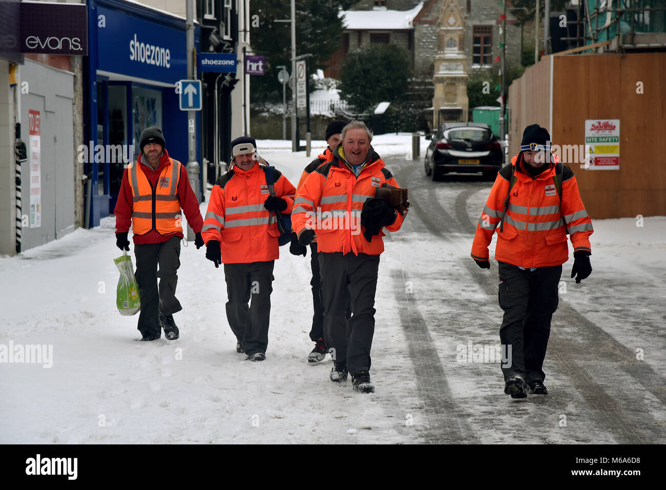 Le immagini mostrano la scena di Bridgend, nel Galles del Sud, questo venerdì dopo la tempesta Emma a sinistra alcuni cm di neve nella sua scia. Bridgend consiglio i lavoratori sono raffigurati lo sgombero neve e ghiaccio off marciapiedi e passaggi pedonali. Royal Mail personale è raffigurato il ritorno a casa non sono in grado di lavorare a causa di avverse condizioni atmosferiche, sono raffigurate nella strada commerciale del centro città. Una macchina viene spinta attraverso la neve in Nolton Street nel centro di Bridgend. Un veicolo 4x4 fa il suo modo attraverso la strada commerciale.. Un lone shopper fa il suo modo di ASDA. Un uomo braves il meteo indossare pantaloni corti durante la rimozione di neve. Foto Stock