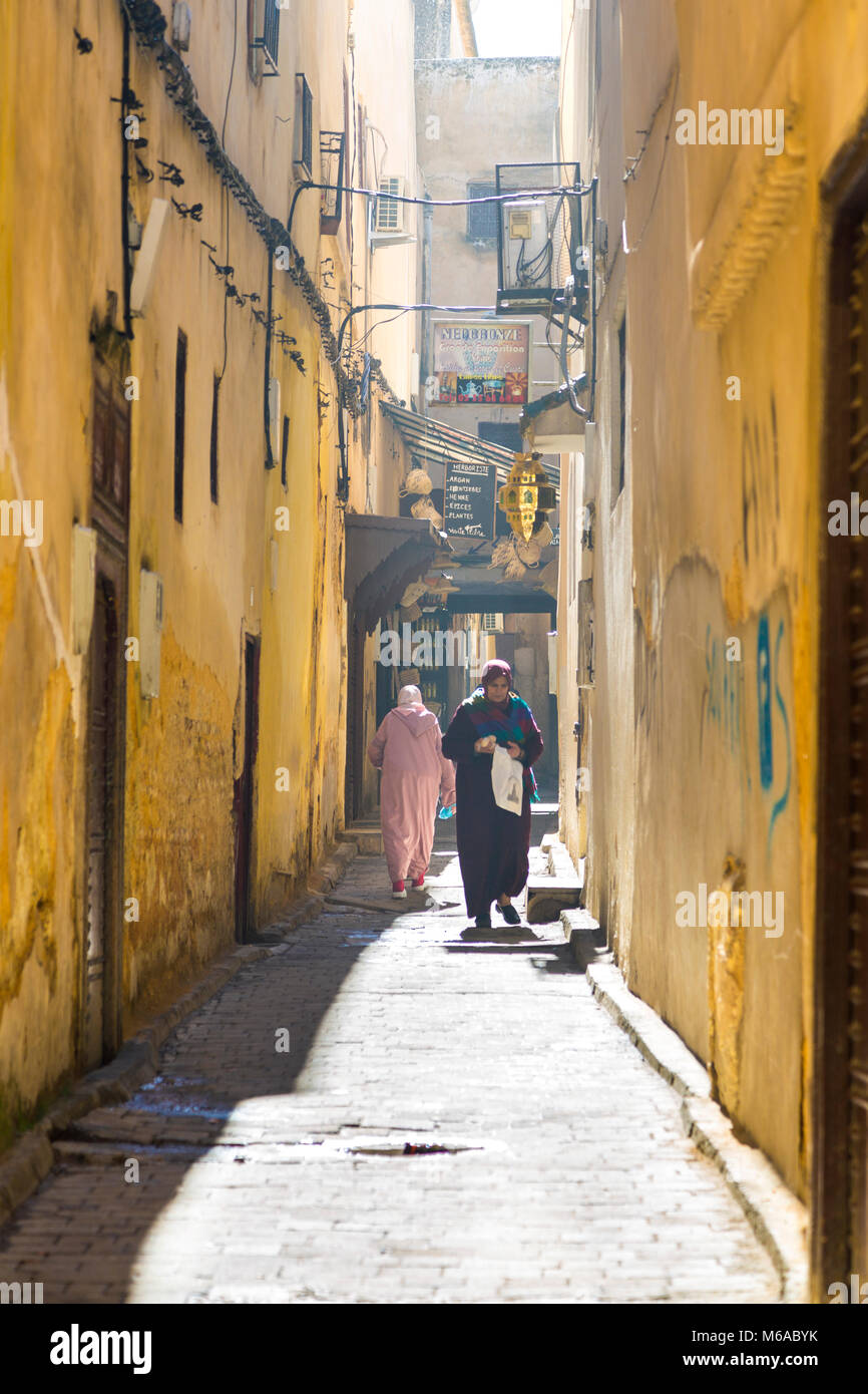 Le donne marocchine in tradizionali abiti musulmani camminare giù per una strada stretta nella medina di Fez, Marocco Foto Stock