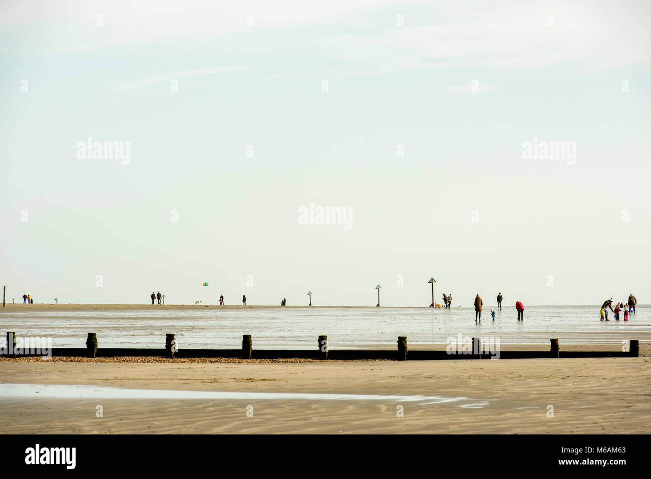 La gente camminare sulla spiaggia di West Wittering, West Sussex, a bassa marea su una fine inverno pieno di sole del pomeriggio. Foto Stock
