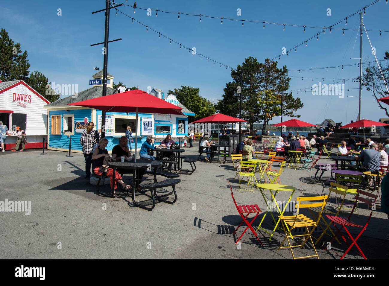 Mangiare fuori sul fronte mare Halifax Nova Scotia sedie gialle tavolo metallo caffè cabina cabine Harbour cafè filo luci cavo sedersi a parlare Foto Stock