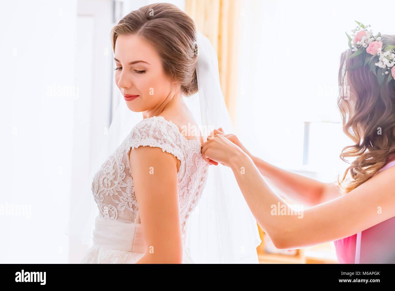 Aiutare la sposa a mettere il suo abito da sposa a Foto Stock