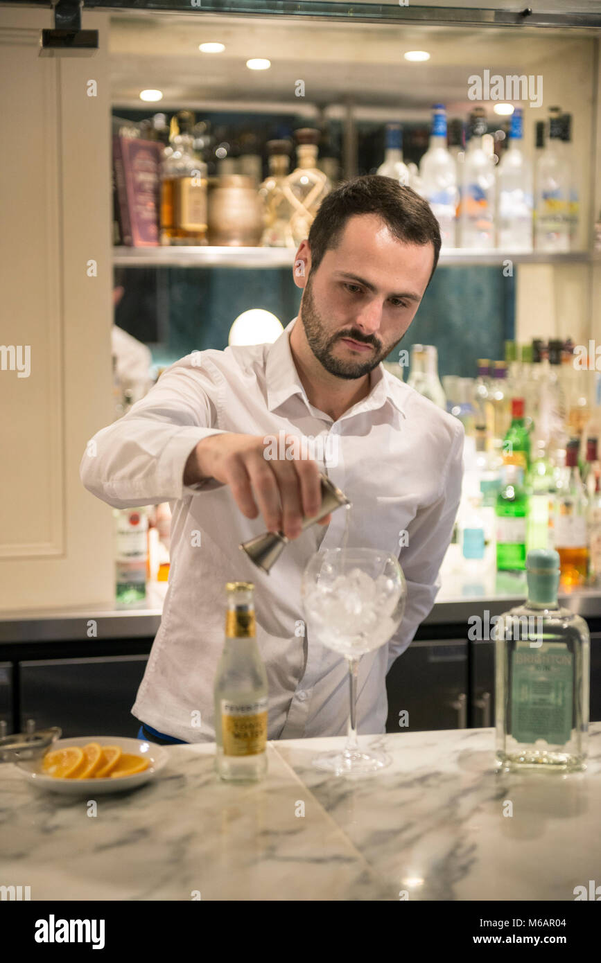 Una barra bianca uomo si mescola un gin tonic in un bar in hotel Foto Stock