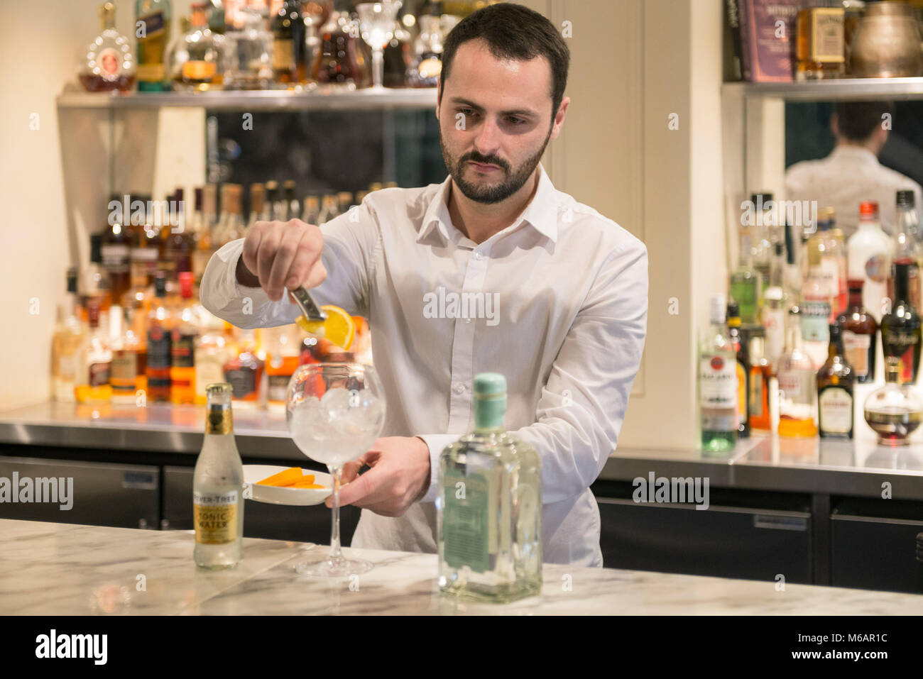 Una barra bianca uomo si mescola un gin tonic in un bar in hotel Foto Stock