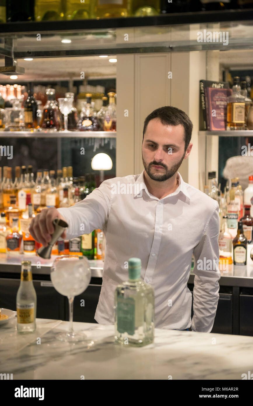 Una barra bianca uomo si mescola un gin tonic in un bar in hotel Foto Stock