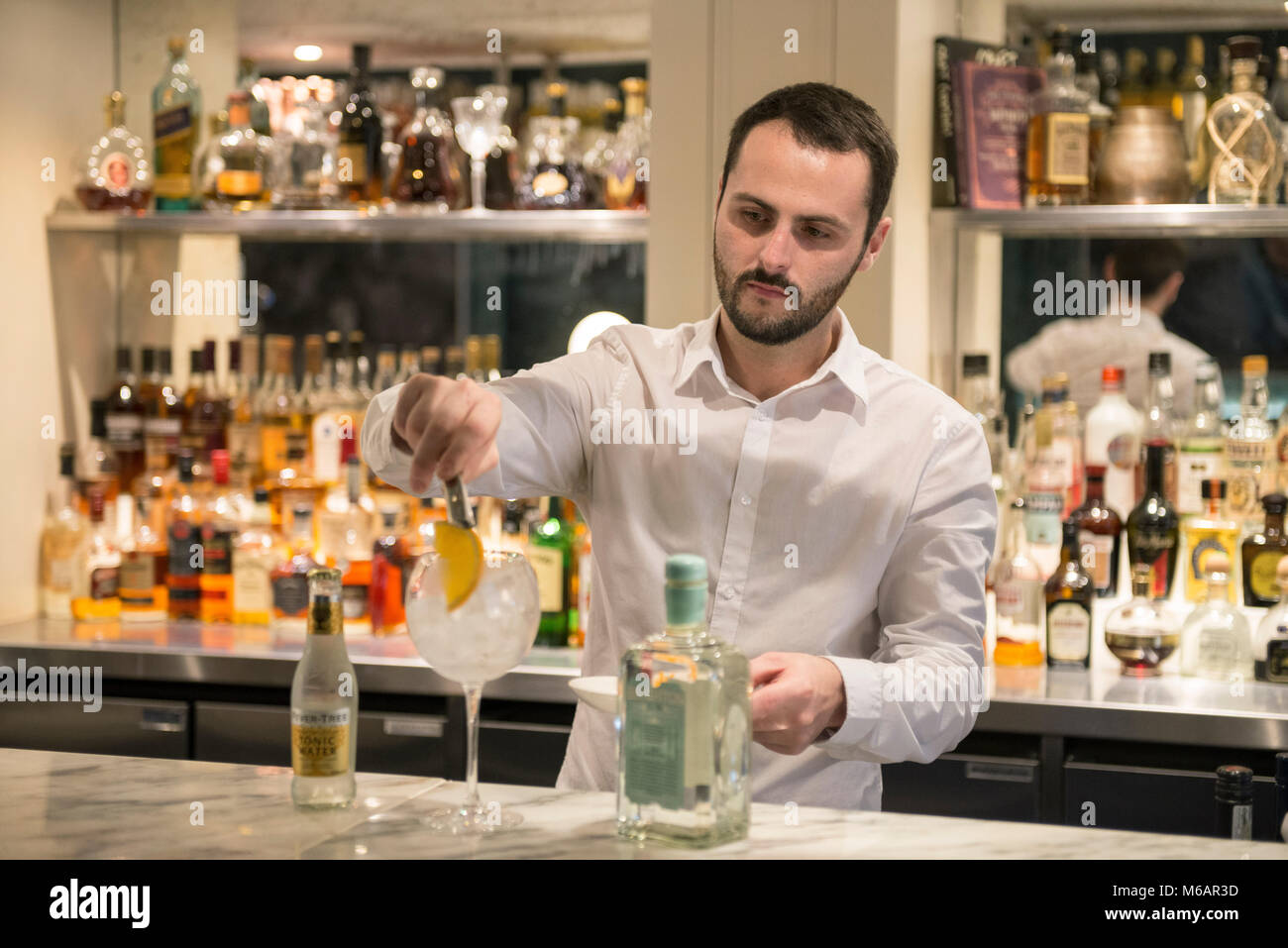 Una barra bianca uomo si mescola un gin tonic in un bar in hotel Foto Stock