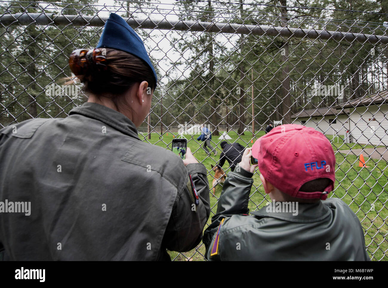 McKay Neel (a destra), McChord della nuovissima pilota per un giorno partecipante, e Senior Airman Skylar Putnam, quarto squadrone Airlift loadmaster, registrare video di un militare di cane da lavoro in azione durante il McKay's tour a base comune Lewis-Mccorda, nello Stato di Washington, il 20 febbraio, 2018. L obiettivo del programma è quello di trarre beneficio dai bambini che hanno gravi o croniche e delle loro famiglie. (U.S. Air Force Foto Stock