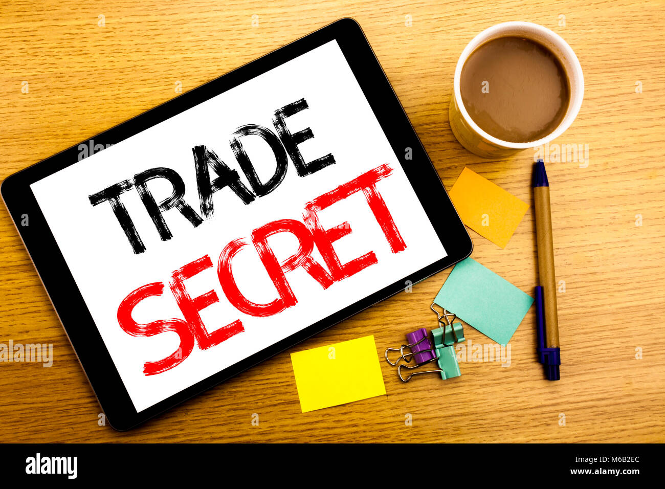 Il testo scritto a mano la didascalia che mostra il segreto commerciale. Il concetto di Business iscritto per la protezione dei dati scritti su tablet, sullo sfondo di legno con una nota adesiva e Foto Stock