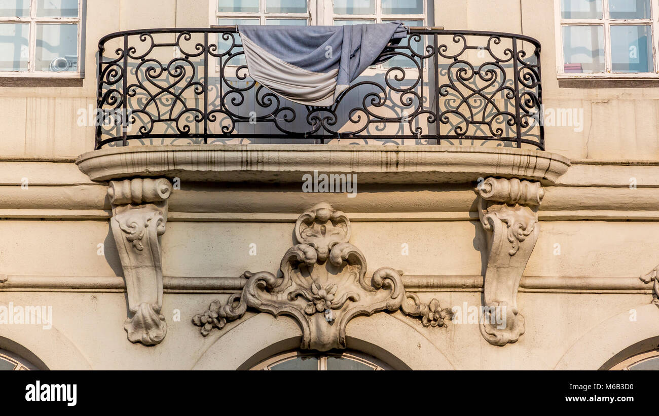 Ornati in ferro battuto balcone su un edificio in pietra che si affaccia sul canale in Bruges drappeggiati con materiale di essiccazione Foto Stock