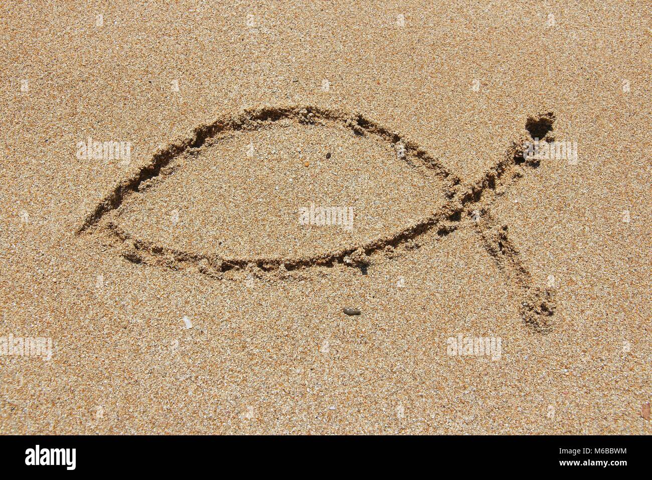 Il simbolo del cristianesimo - forma religiosa tracciata nella sabbia. Il cattolicesimo pesce - ichthus. Foto Stock